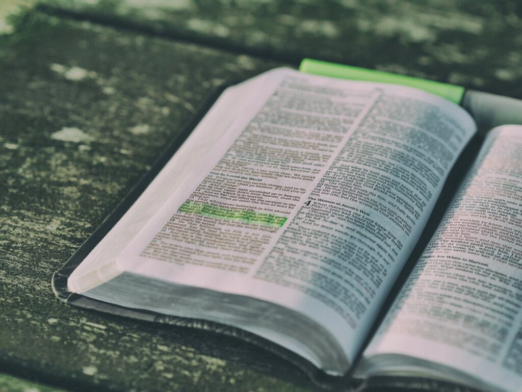 Image used for biblical meditation. Open bible on a wooden table with a verse highlighted by green highlighter